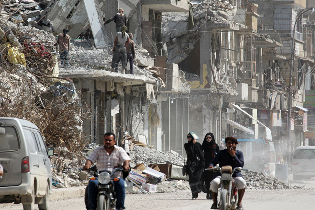 Women walk past rubble of damaged buildings in Raqqa, Syria, on May 14 (Reuters photo)