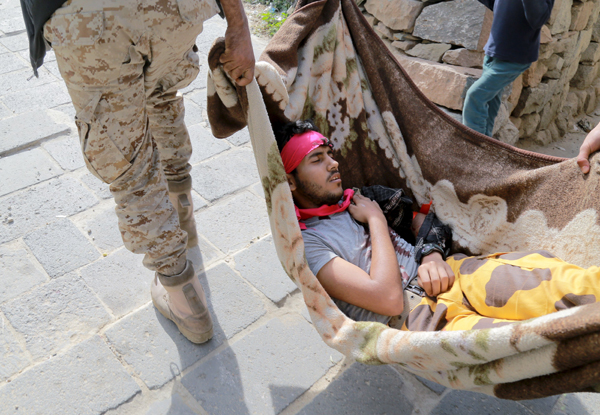 A fighter of the pro-government Popular Resistance Committees is carried on a blanket after he was injured during clashes with Houthi fighters in Yemen’s southwestern city of Taez, Tuesday (Reuters photo)