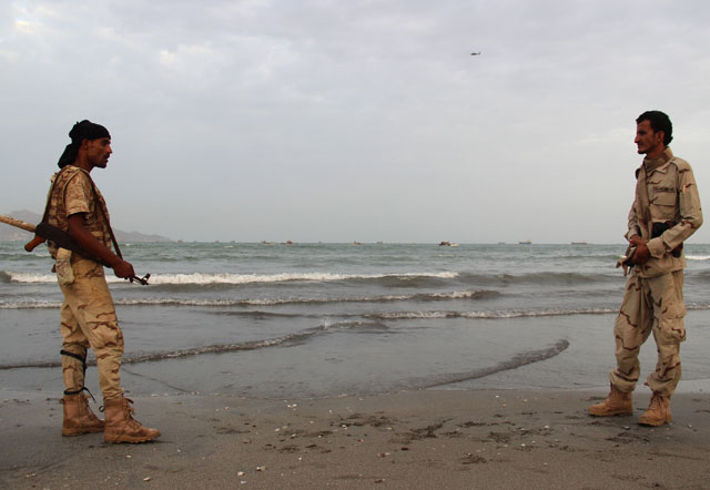 Pro-government forces stand on the beach in the southern coastal city of Aden as Yemeni coast guards search for the remains of a United Arab Emirates helicopter from the Saudi-led coalition backing government forces in Yemen after it crashed, on Monday (AFP photo)