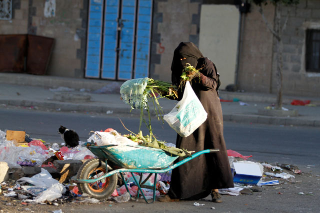 A woman collects recyclable items from garbage along a street in Sanaa, Yemen, on Thursday (Reuters photo)