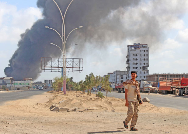 A fighter from the separatist Southern Transitional Council walks with smoke billowing in the background in the government's de facto capital Aden on Wednesday (AFP photo)