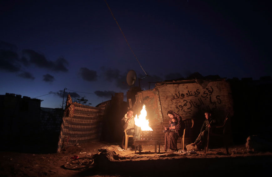 In this Sunday photo, members of a Palestinian family warm themselves up near a fire outside their makeshift house during a power cut in a poor neighbourhood in the town of Khan Younis in the southern Gaza Strip (AP photo)