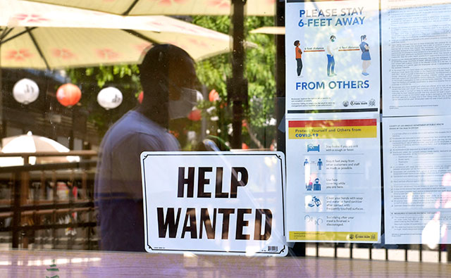 In this file photo taken on May 28, 2021, a 'Help Wanted' sign is posted beside Coronavirus safety guidelines in front of a restaurant in Los Angeles, California. (AFP photo)
