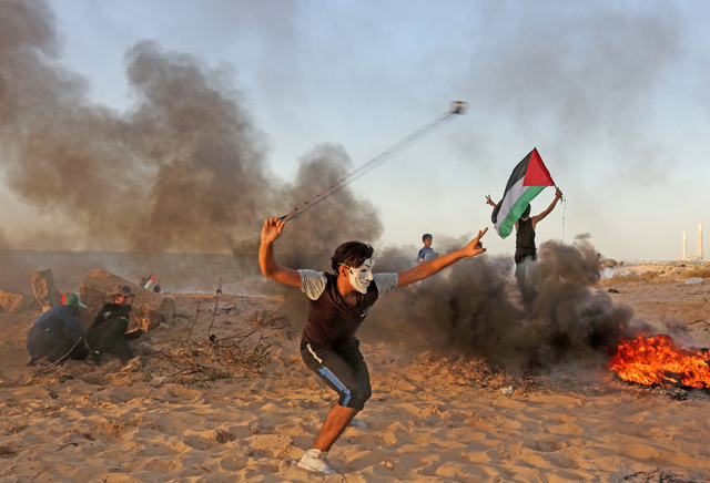 A Palestinian protester uses a slingshot to hurl stones during a demonstration on the beach near the maritime border with Israel, in Beit Lahia in the northern Gaza Strip, on Monday (AFP photo)