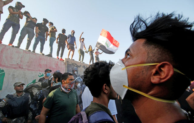 Iraqi protesters stand on concrete blast walls during a protest near the building of the government office in Basra, Iraq, on Wednesday (Reuters photo)