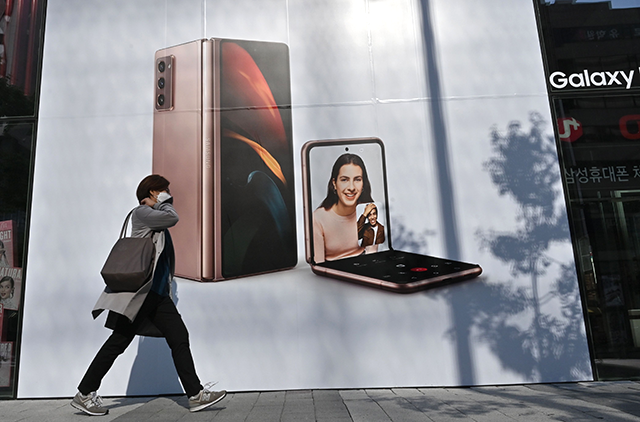 A woman walks past an advertisement for the Samsung Galaxy Z Fold2 and Z Flip smartphones at a Samsung Electronics store in Seoul on Thursday (AFP photo)