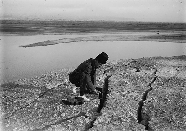 A man using his rifle to test the depth of a crack caused by the 1927 earthquake (Photo courtesy of CBRL Amman Institute)