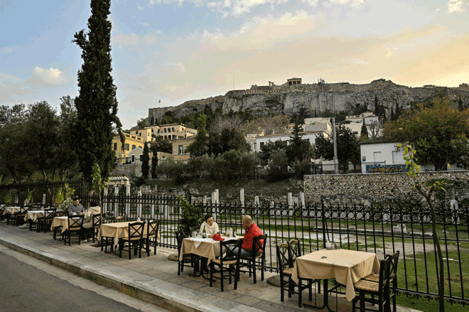 Tourists sit in an outdoor cafe-restaurant at the popular tourists Plaka area of Athens, before the sunset, on December 8 (AFP photo)