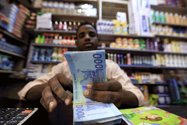 A Sudanese shop owner counts a stack of cash at a grocery store in the capital Khartoum, on January 19, 2023 (AFP photo)