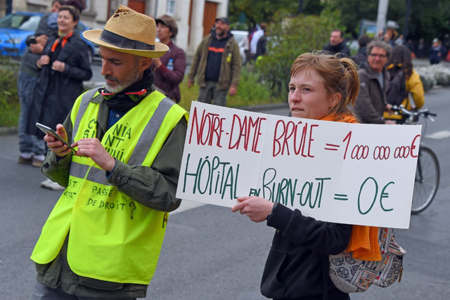 A protester holds a placard reading in French ‘Notre-Dame [of Paris] = 1 million euros, Burn out at hospitals = zero euro’ on a street in Bordeaux, south-western France, during a demonstration called by the yellow vest movement for a 24th consecutive week, on Saturday (AFP photo)