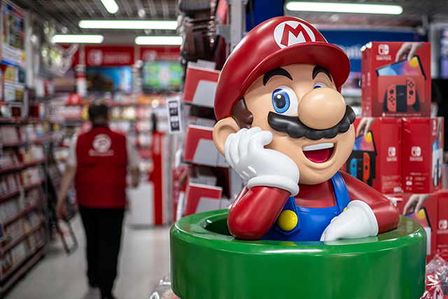 Nintendo character Mario is seen as an employee (left) walks past in the gaming section for Nintendo Switch products at a shop in Tokyo on Thursday (AFP photo)