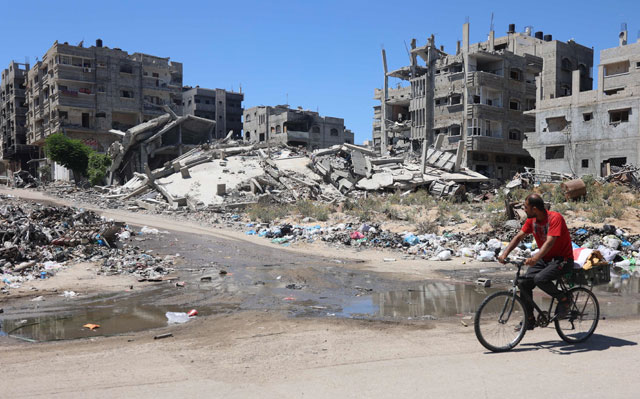 A Palestinian man cycles past open sewage and buildings destroyed in past Israeli bombardment, in the Sheikh Radwan neighbourhood, north of Gaza City on Wednesday (AFP photo)