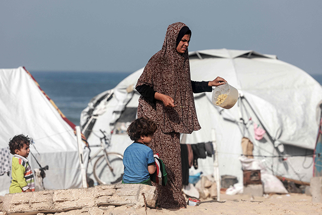 A displaced Palestinian woman walks near tents at a makeshift camp for displaced people in Rafah in the southern Gaza Strip on Saturday (AFP photo)