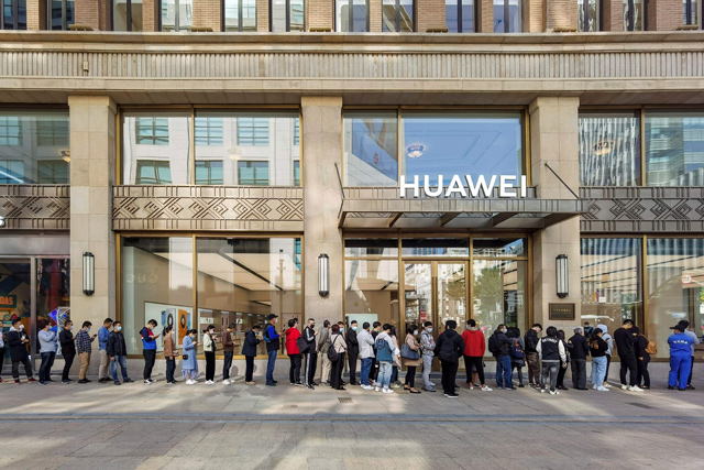 People wearing masks wait in line in front of Huawei’s flagship store for pre-sales of the newly launched Huawei Mate40 mobile phone series in Shanghai, on Friday (AFP photo)