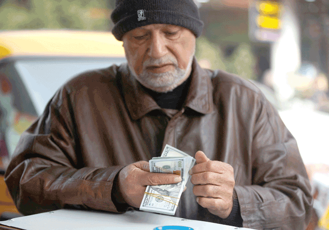 A man counts US dollar banknotes at Al Kifah stock market in Baghdad on Tuesday as the value of Iraqi dinar against US dollar drops further (AFP photo)