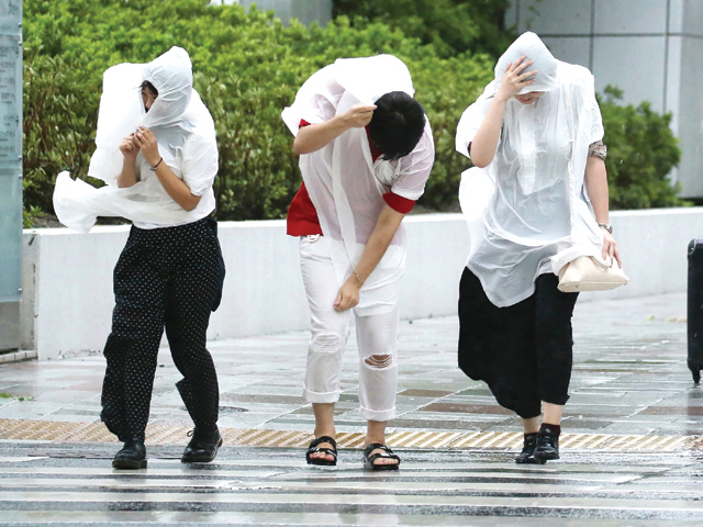 People walk against strong winds in Nagoya, on Tuesday, as Typhoon Jebi made landfall around midday in southwestern Japan (AFP photo)