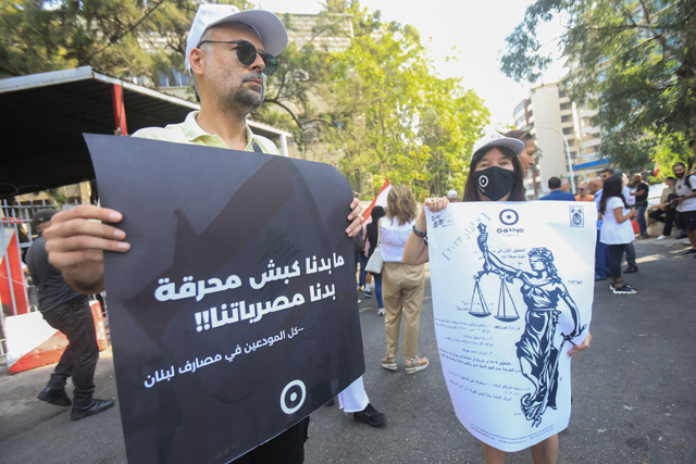 Protesters lift placards during a rally outside the Palace of Justice in Beirut where Lebanon's former Central Bank chief Riad Salameh is set to attend a questioning hearing on Monday. (AFP photo)
