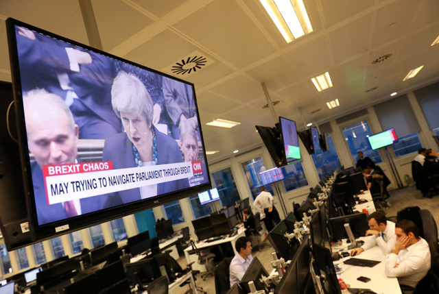 Britain's Prime Minister Theresa May is seen on a large television as traders work at CMC markets in London, Britain, on Tuesday (Reuters photo)