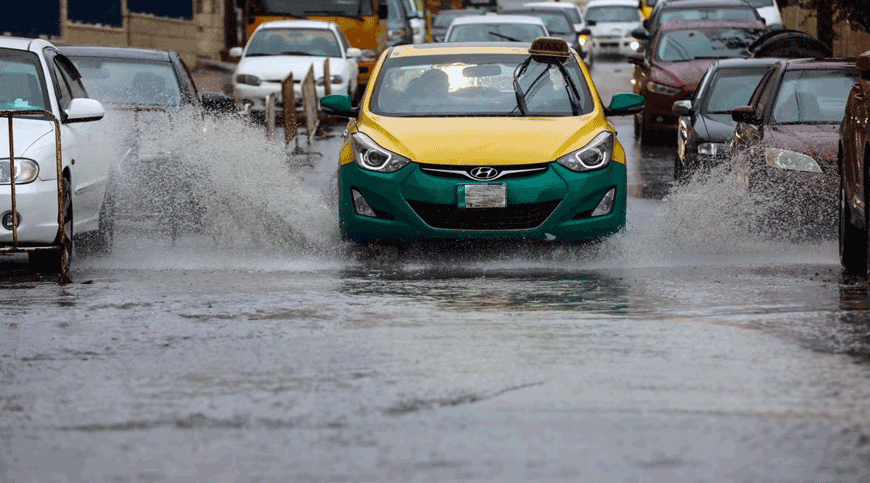 Vehicles make their way through a waterlogged street after rain in Amman on Monday  (Photo by Osama Aqarbeh)