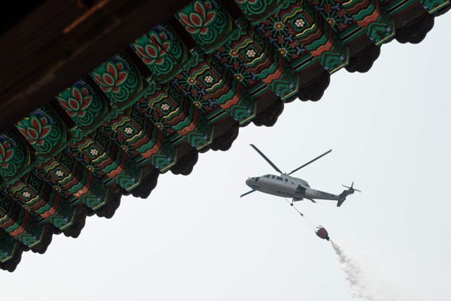 A helicopter drops water as they prepare for the possibility of a wildfire advancing towards Gounsa Temple in Uiseong today (AFP photo)