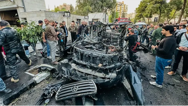 Syrian emergency and security services inspect the wreckage of a car that exploded in the Syrian Capital Damacus on Monday (AFP photo)