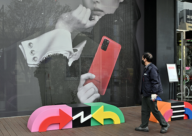 A man walks past an advertisement for the Samsung Galaxy S20 5G smartphone at a telecom shop in Seoul on April 7, 2020. (AFP photo)