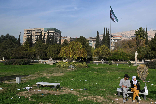A couple sit on a bench in Damascus' central Umayyad Square on Thursday (AFP photo)