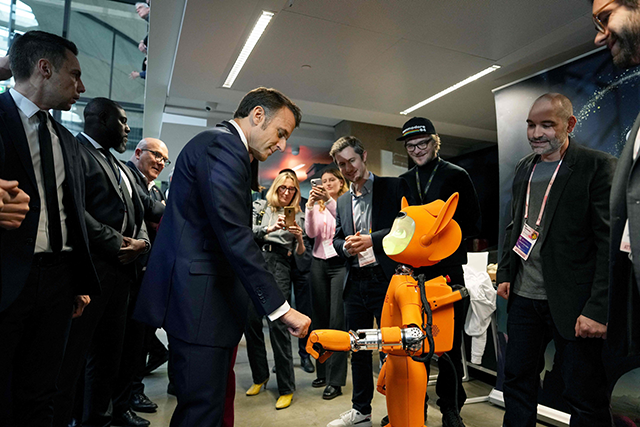 French President Emmanuel Macron (centre left) bumps fists with a robot during a visit at the startup campus Station F as part of an event on the sidelines of the Artificial Intelligence Action Summit in Paris, on Tuesday (AFP photo)