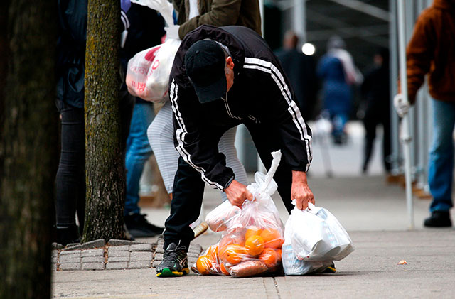 A man carries bags with food as Volunteers from City harvest distribute food in Harlem in New York City, on March 28 (AFP photo)