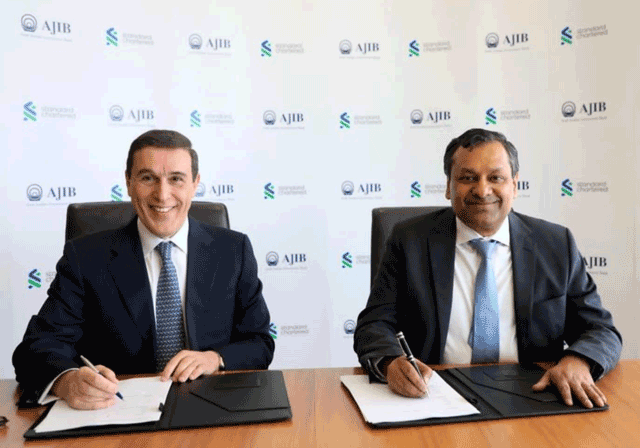 Hani Al Qadi, chairman of the board of directors of AJIB (left), Akil Mahesh, Head of Strategic Projects, AME, Standard Chartered Bank, sign an agreement on Sunday (Photo courtesy of AJIB)