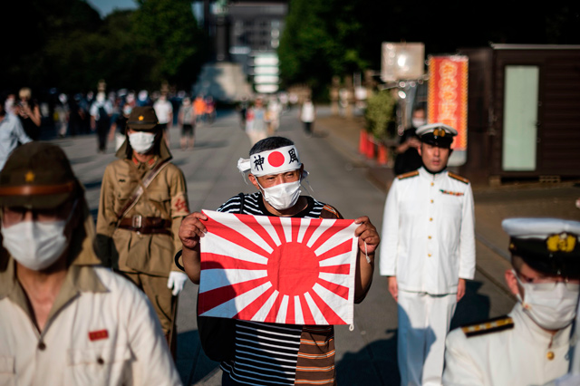 A man holds a Rising Sun flag amongst others wearing period Japanese Imperial Army and Navy uniforms outside the Yasukuni shrine in Tokyo on Saturday, on the 75th anniversary of Japan’s surrender in World War II (AFP photo)  