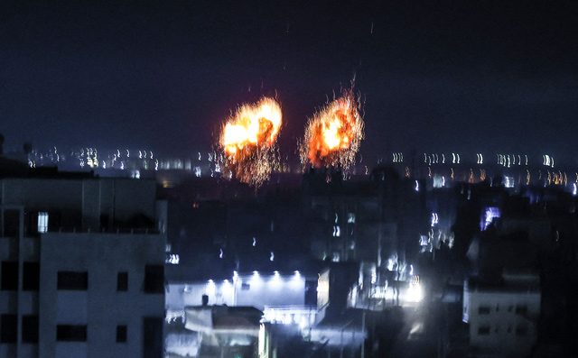 Explosions light-up the night sky above buildings in Gaza City as Israeli forces shell the Palestinian enclave, early on Wednesday (AFP photo)