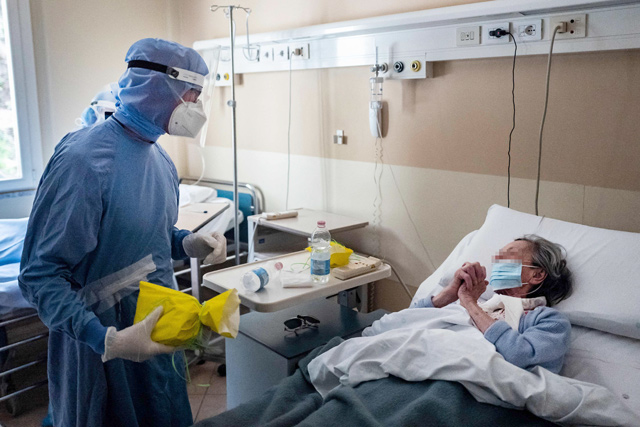 A patient infected with COVID-19 reacts before receiving a Colomba traditional Easter cake handed by Doctor Paolo Russo (left) on Sunday at the COVID ward of the GVM Maria Pia Hospital in Turin, as staff visits patients infected with COVID-19 to offer them cakes for Easter (AFP photo)