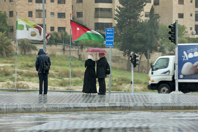 Commuters are seen on a roadside on a rainy day in Amman (JT  file photo)