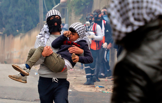 A Palestinian protester assists a youth reacting to tear gas, amid confrontations with Israeli forces in the village of Kfar Qaddum near the Jewish settlement of Qadumim (Kedumim) in the occupied West Bank, during a demonstration against the expropriation of land by Israel, on Friday (AFP photo)