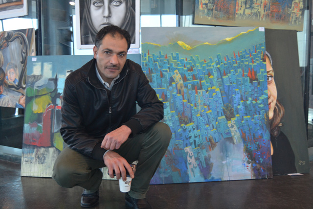 In this photo taken on Thursday, Iraqi artist Nabeel Al Jabouri kneels in front of his paintings at a UN bazaar in Amman  (Photo by Ana V. Ibáñez Prieto)