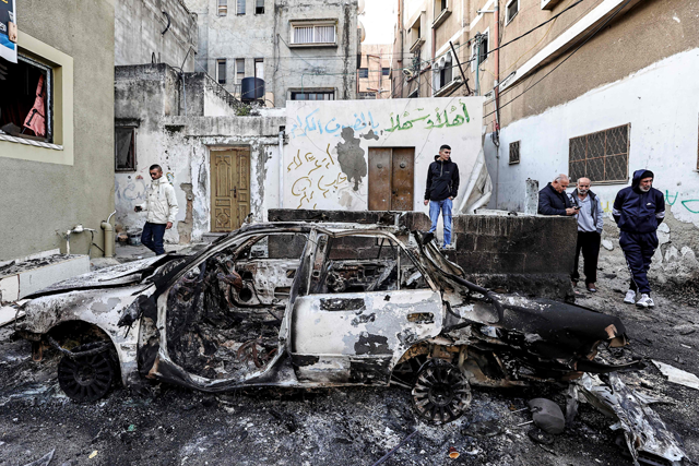 Palestinians inspect the remains of a burnt vehicle in the aftermath of an Israeli raid in the Nur Shams camp for Palestinian refugees near the northern city of Tulkarm in the occupied West Bank on Wednesday (AFP photo)