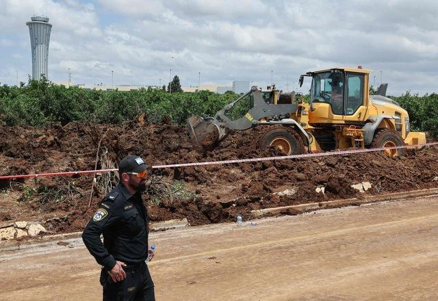 Members of Israeli security services fill up a crater near a road outside Israel's Ben Gurion airport after a missile launched from Yemen struck the area on May 4, 2025 (AFP photo)