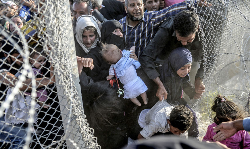 Syrians fleeing the war rush through broken border fences to illegally enter Turkish territory, near the Turkish border crossing at Akcakale in Sanliurfa province, on Sunday (AFP photo)
