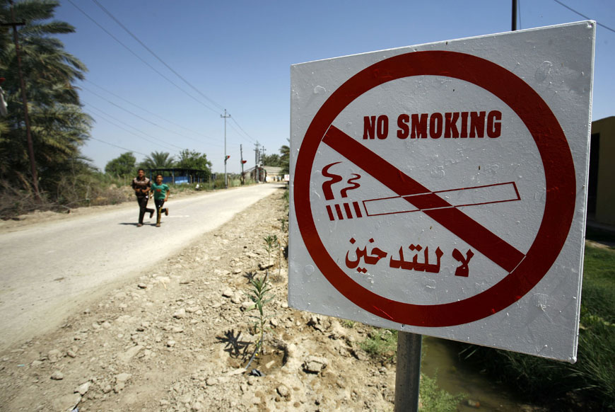 Iraqi youhts run near a sign indicating that smoking is forbidden in the southern Iraqi village of Albu Nahadh, in the Al Saniya area in Iraq's southern Al Diwaniyah province, on June 15 (AFP photo)