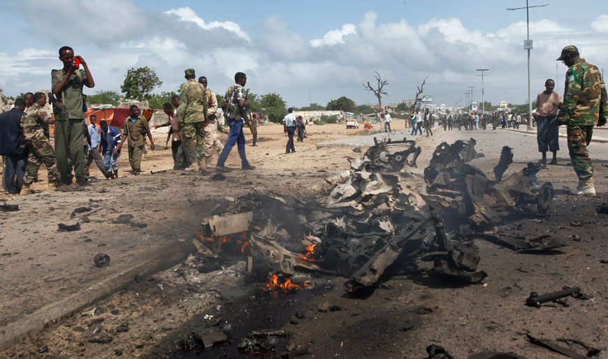 Somali soldiers stand near the wreckage at the scene of a suicide car bomb attack which targeted a convoy of foreign officials in Mogadishu, Somalia, Wednesday (AP photo)