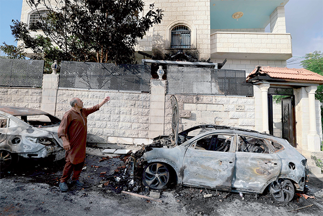 A man standing next to burnt cars points at the damage in his house, a day after an attack by Zionist settlers on the village of Jit near Nablus in the occupied West Bank that left a 23-year-old man dead and others with critical gunshot wounds, on Friday (AFP photo)