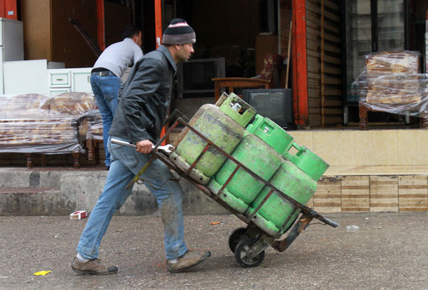 A worker pushes a cart filled with gas cylinders in a street in Amman on Saturday. Sales of gas cylinders, used for heating purposes, tend to rise substantially ahead of expected snowstorms  (Photo by Hassan Tamimi)