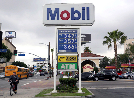 A cyclist rides by a Mobil gas station in Los Angeles (AP photo)