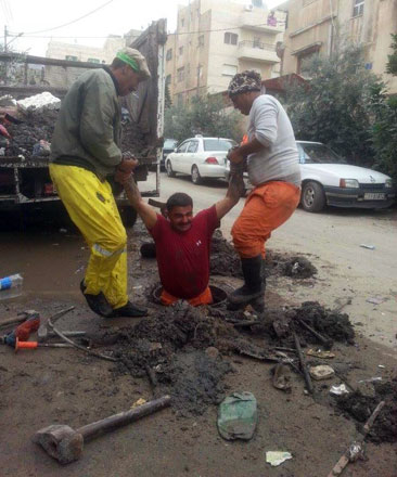 Greater Amman Municipality employees clear a manhole on a street in the capital this week (Photo courtesy of GAM)