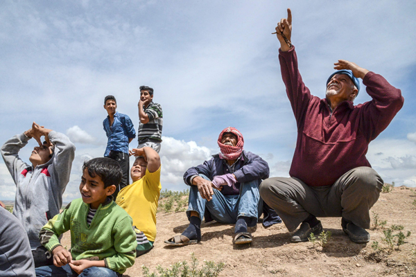 People look on as war-planes carry out bombing nearby in Kilis on Saturday (AFP photo)