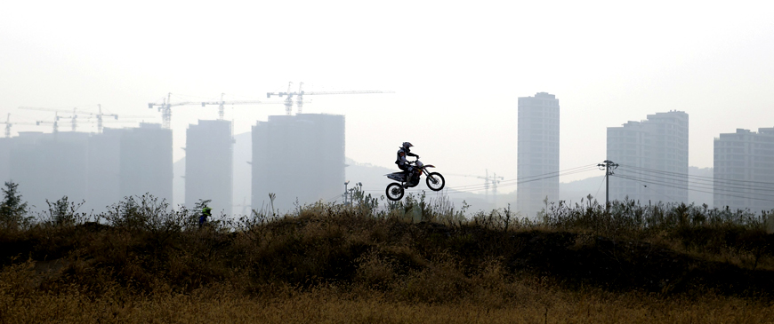 A motorcyclist practises near buildings in construction in Qingdao, Shandong province, China last week. Home prices in China rose for a fifth consecutive month in September, suggesting a mild recovery in the housing market that will relieve some pressure on the struggling economy (Reuters photo)
