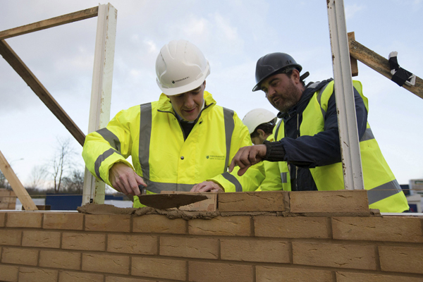 Britain's Chancellor of the Exchequer George Osborne (left) is shown how to lay a brick by bricklaying supervisor Michael Hull during a visit to a housing development in South Ockendon in Essex, Britain, on Thursday (Reuters photo)