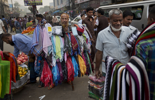 In this December 8 photo, Bangladeshi street vendors stand on a busy road and wait for customers in Dhaka (AP photo)