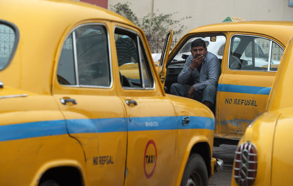 In this photo taken on Thursday, an Indian taxi driver sits in his vehicle as he waits for passengers in Kolkata (AFP photo)